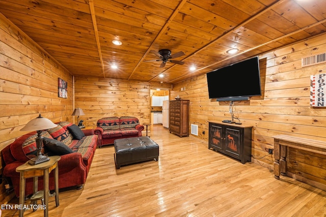 living area with ceiling fan, wooden ceiling, light wood-style flooring, wooden walls, and visible vents