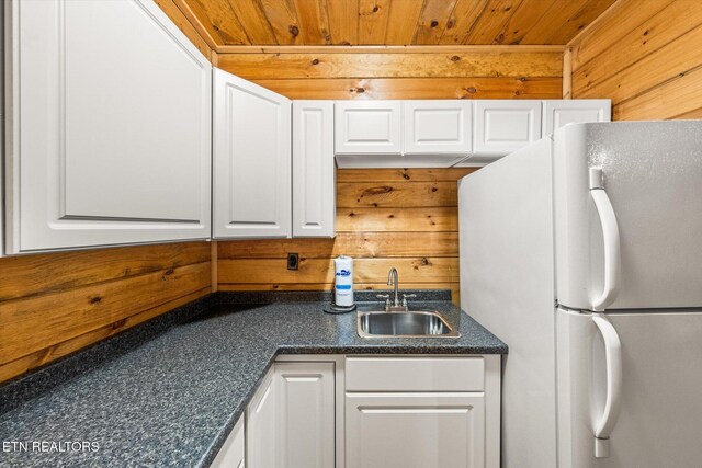 kitchen featuring a sink, wood ceiling, white cabinets, freestanding refrigerator, and dark countertops