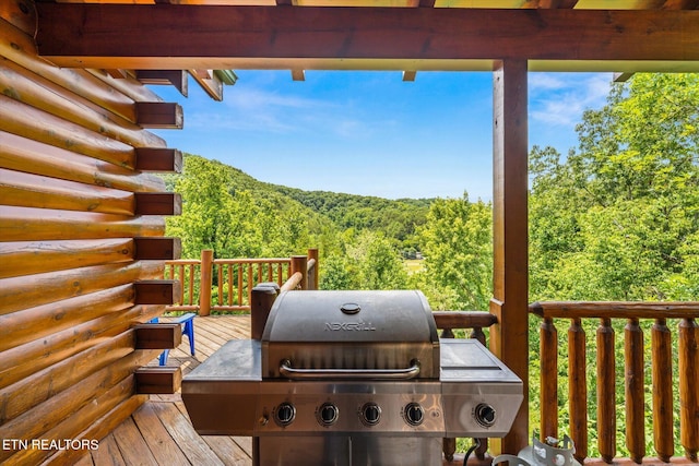 deck with a grill and a view of trees