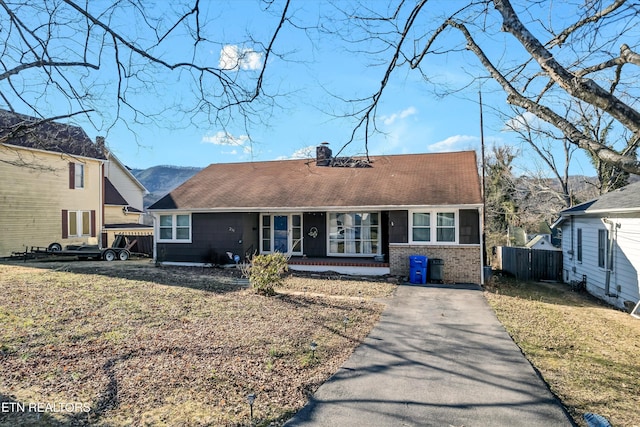 ranch-style home with a chimney, a shingled roof, fence, driveway, and a front lawn