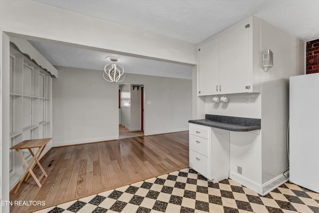 kitchen featuring a textured ceiling, white cabinetry, baseboards, tile patterned floors, and dark countertops