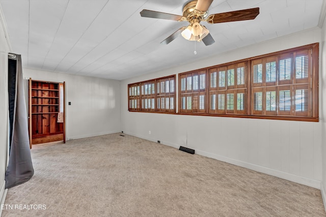 carpeted empty room featuring a ceiling fan and baseboards