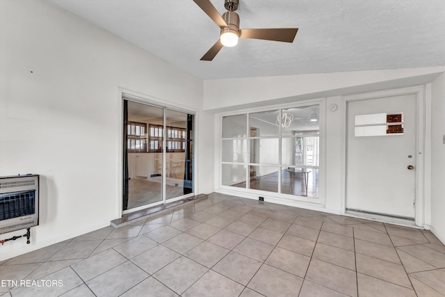 interior space with a wealth of natural light, lofted ceiling, heating unit, and a ceiling fan