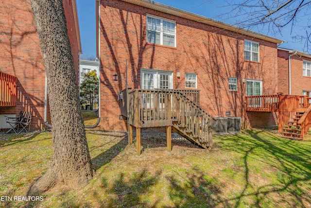 rear view of property featuring brick siding, a lawn, stairway, cooling unit, and a wooden deck