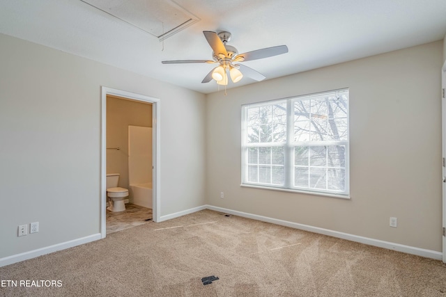 unfurnished bedroom featuring ensuite bath, carpet, attic access, and baseboards