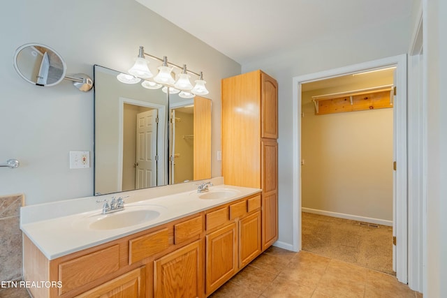 full bath featuring double vanity, tile patterned flooring, baseboards, and a sink