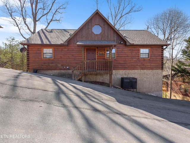 log-style house with a shingled roof and log siding