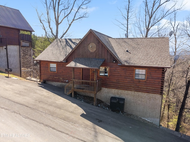 view of front of property with log siding and roof with shingles