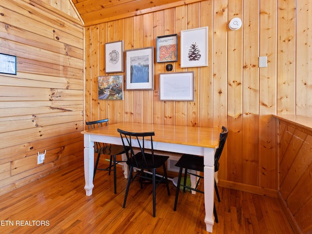 dining room featuring wood walls, breakfast area, and wood finished floors