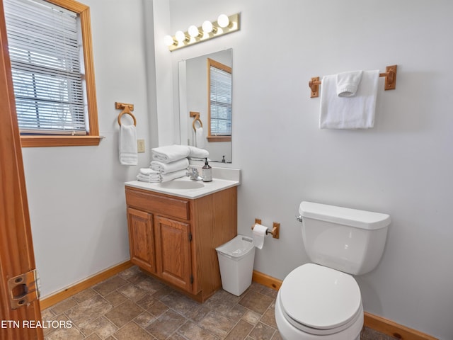 bathroom with toilet, baseboards, and stone finish floor