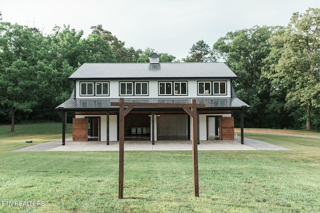 back of house featuring metal roof, a patio area, a yard, and brick siding