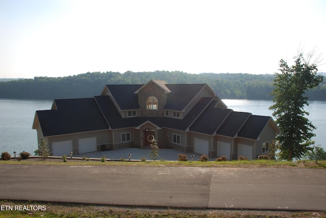 view of front of house with a water view, a garage, and a view of trees