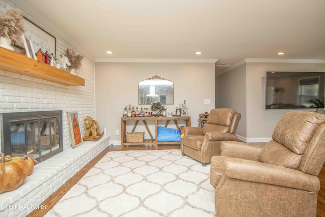 living area with baseboards, wood finished floors, crown molding, a brick fireplace, and recessed lighting