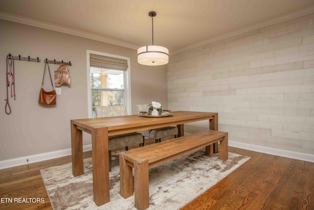 dining space with brick wall, ornamental molding, wood finished floors, and baseboards