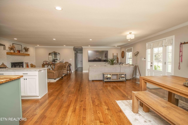 unfurnished dining area with crown molding, recessed lighting, a fireplace, and light wood-style floors