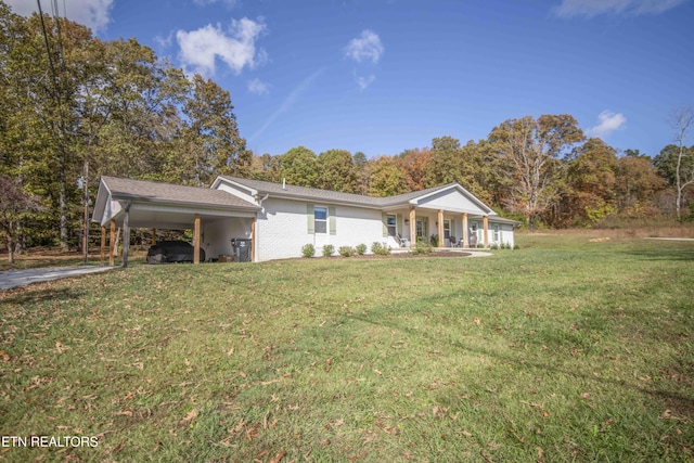 rear view of property with a carport, a porch, a lawn, and brick siding