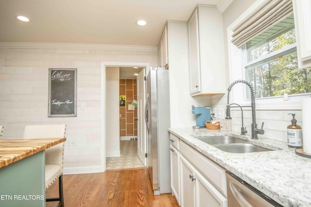 kitchen with stainless steel appliances, light wood-style floors, white cabinets, and a sink