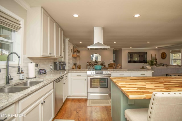 kitchen with stainless steel appliances, a peninsula, a sink, open floor plan, and island exhaust hood