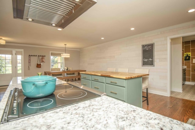 kitchen with butcher block counters, ornamental molding, wood finished floors, green cabinetry, and exhaust hood