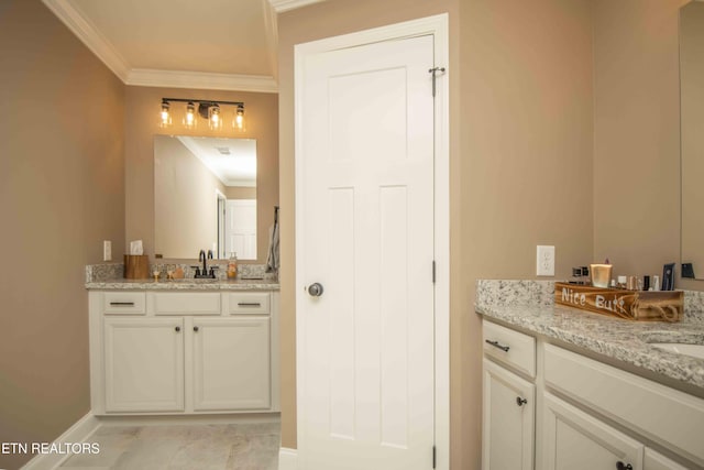 bathroom with baseboards, ornamental molding, two vanities, and a sink