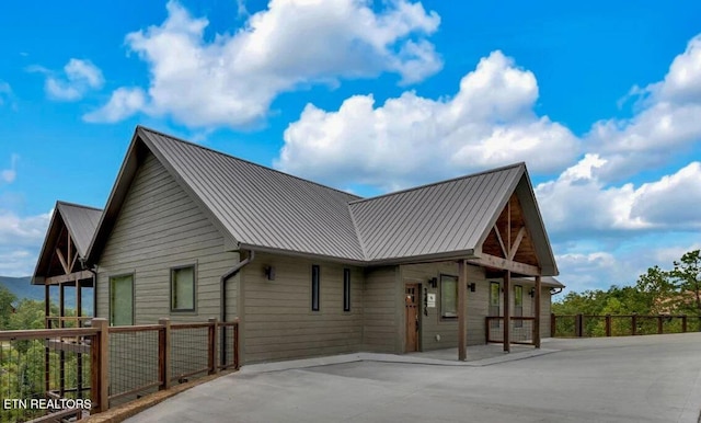 view of property exterior with metal roof, a standing seam roof, and fence