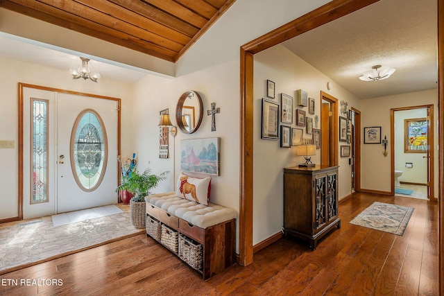 foyer entrance featuring a notable chandelier, wooden ceiling, wood-type flooring, and a wealth of natural light