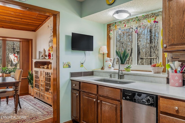 kitchen featuring brown cabinets, light countertops, dishwasher, and a sink