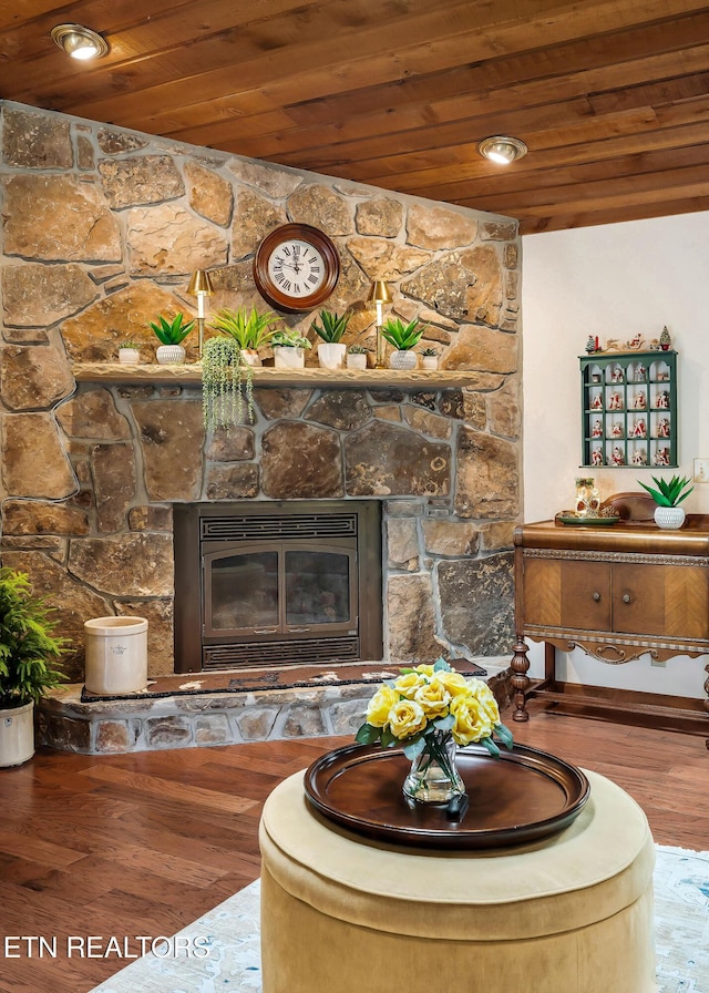 living room with a stone fireplace, wood finished floors, and wood ceiling