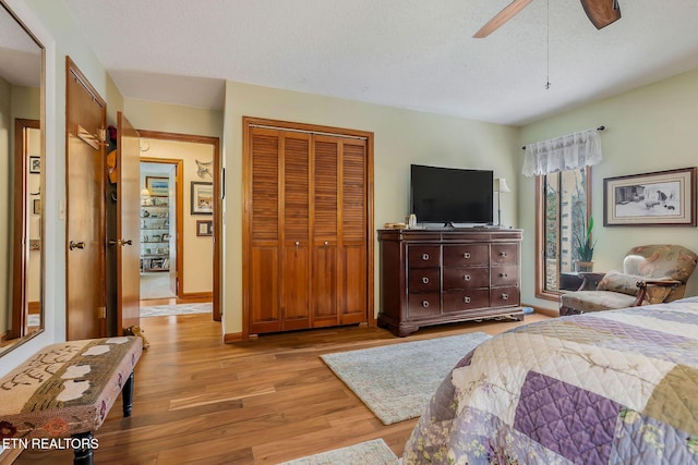 bedroom with a textured ceiling, a ceiling fan, baseboards, a closet, and light wood-type flooring