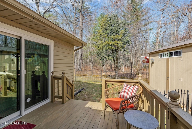 wooden terrace featuring an outbuilding and fence