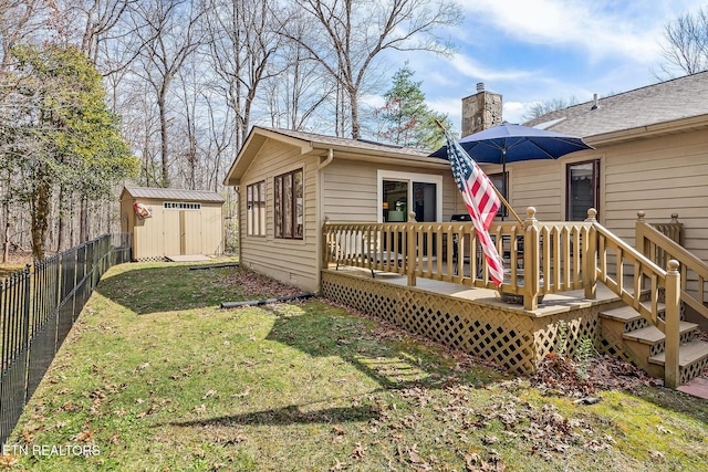 back of property with a fenced backyard, a chimney, an outbuilding, a deck, and a shed