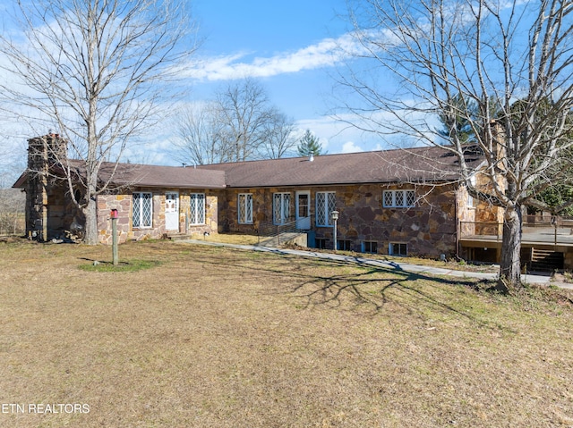 view of front of property featuring stone siding, a front lawn, and a chimney