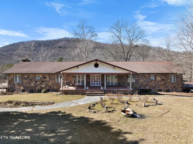 view of front facade featuring stone siding, a front lawn, and a porch