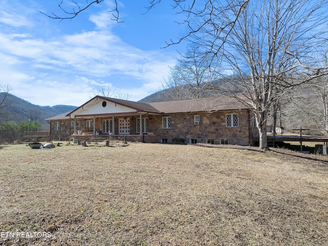 back of property featuring stone siding, a mountain view, and covered porch