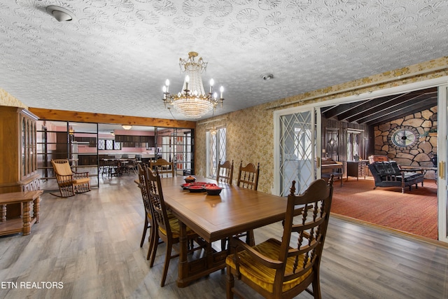 dining room featuring an inviting chandelier, a textured ceiling, and wood finished floors