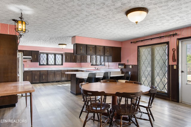 dining area with a textured ceiling and light wood finished floors