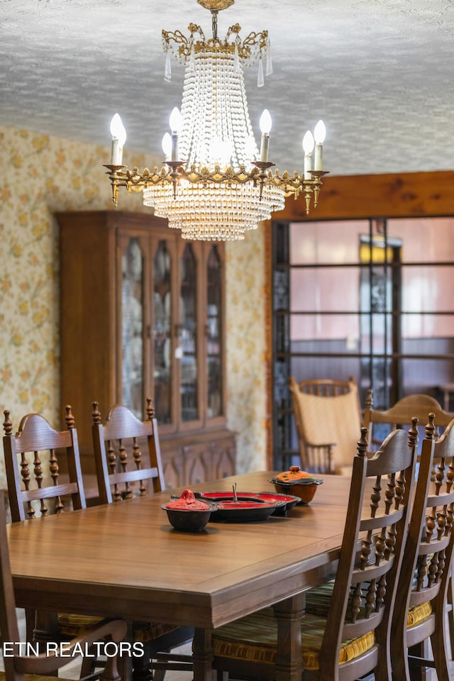 dining space featuring a notable chandelier, a textured ceiling, and wallpapered walls