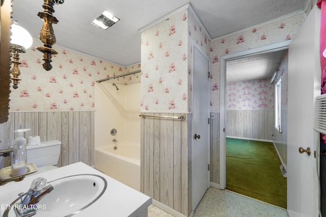 full bathroom featuring wainscoting, a textured ceiling, and wallpapered walls