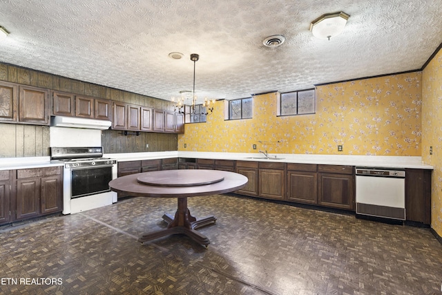 kitchen with white dishwasher, under cabinet range hood, a sink, visible vents, and gas stove