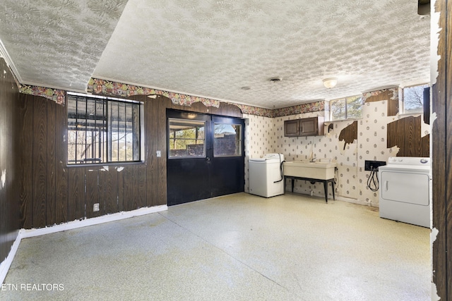 interior space featuring washer / dryer, wallpapered walls, baseboards, and a textured ceiling