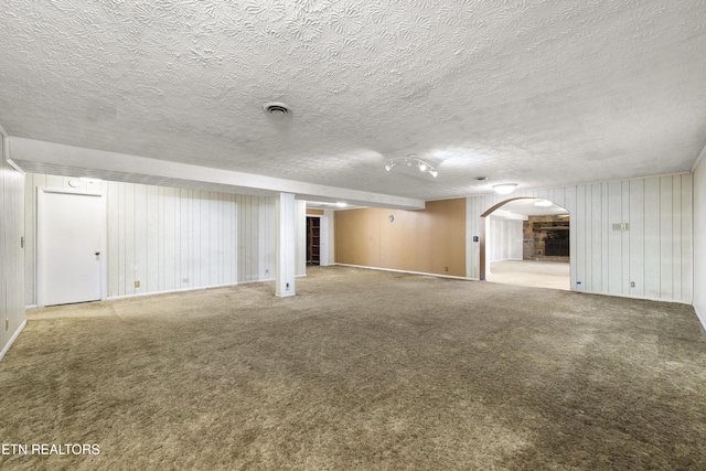 interior space with carpet, visible vents, arched walkways, and a textured ceiling