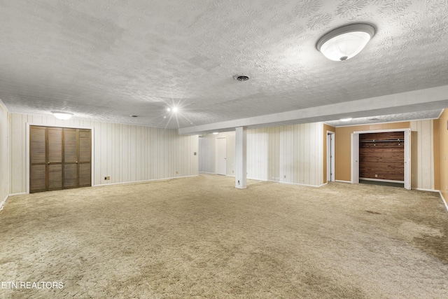 finished below grade area featuring carpet floors and a textured ceiling