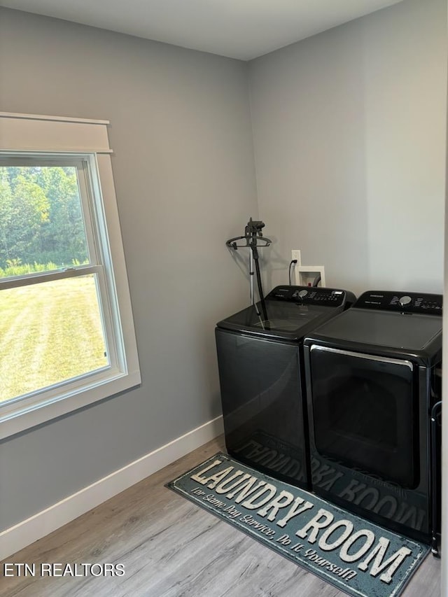 clothes washing area with laundry area, baseboards, wood finished floors, and washing machine and clothes dryer