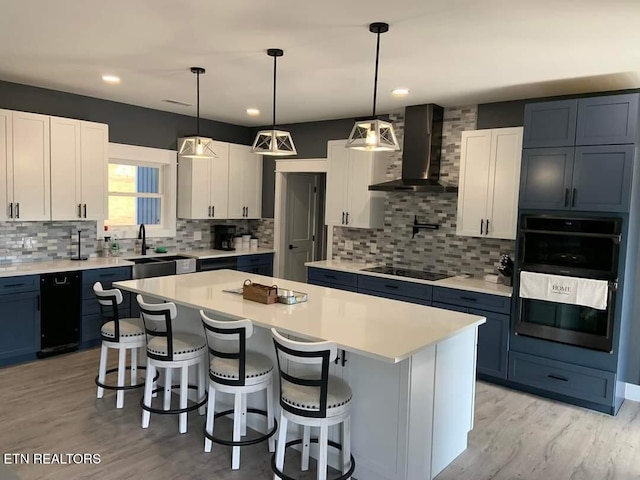 kitchen with wall chimney exhaust hood, a breakfast bar, a center island, double wall oven, and black electric stovetop