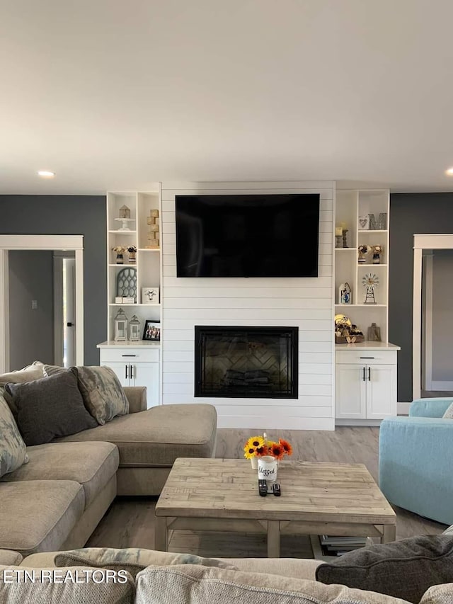 living room featuring a fireplace, wood finished floors, and recessed lighting