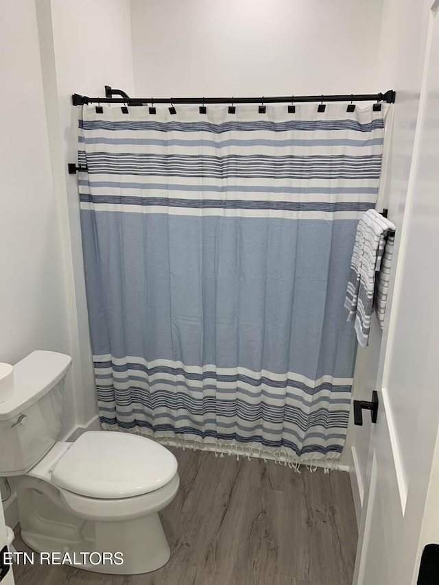 bathroom with a shower with shower curtain, wood finished floors, and toilet