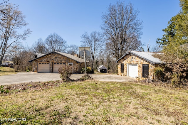 view of side of home featuring a garage, stone siding, and a yard