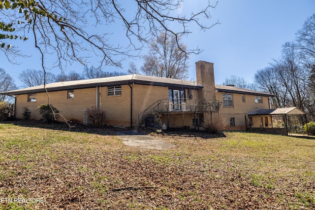 rear view of property featuring a wooden deck, a chimney, stairs, a yard, and brick siding