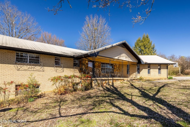 view of front of property featuring covered porch, brick siding, and a front lawn