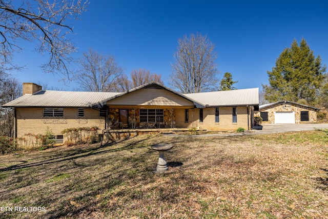 ranch-style house with metal roof, a porch, brick siding, an outdoor structure, and a chimney